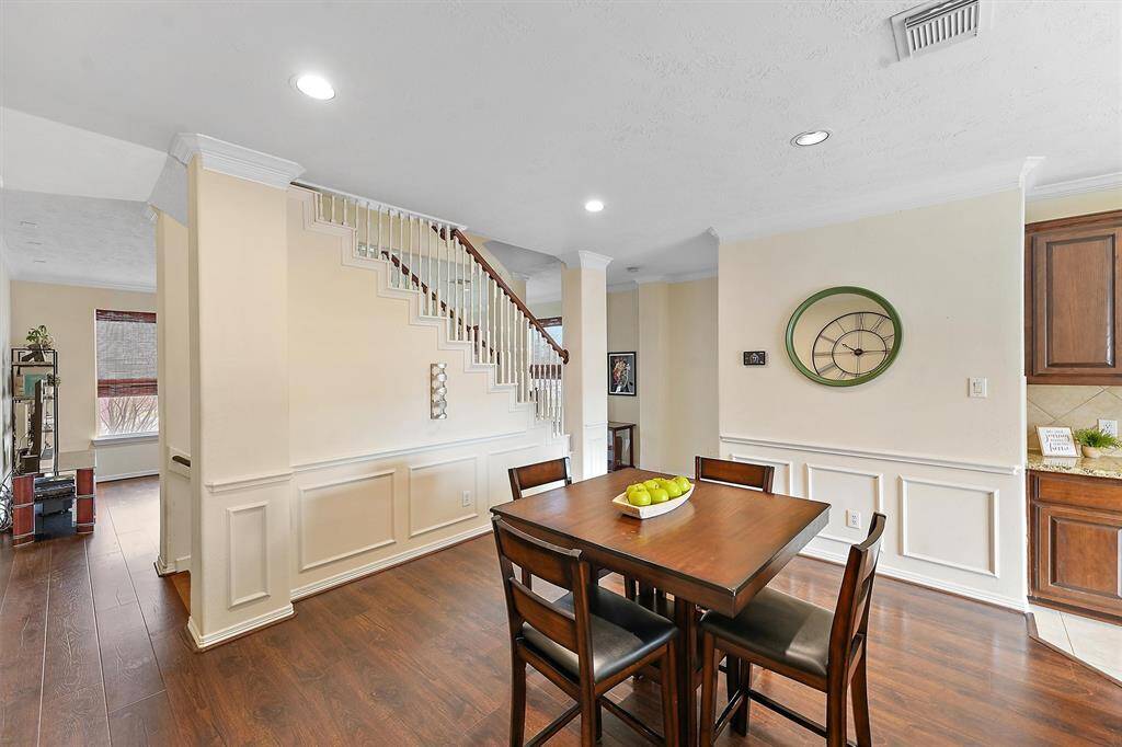 Dining space adjacent to the second level staircase with the living area on the other side. Staircase leads up to the third level with bedrooms.