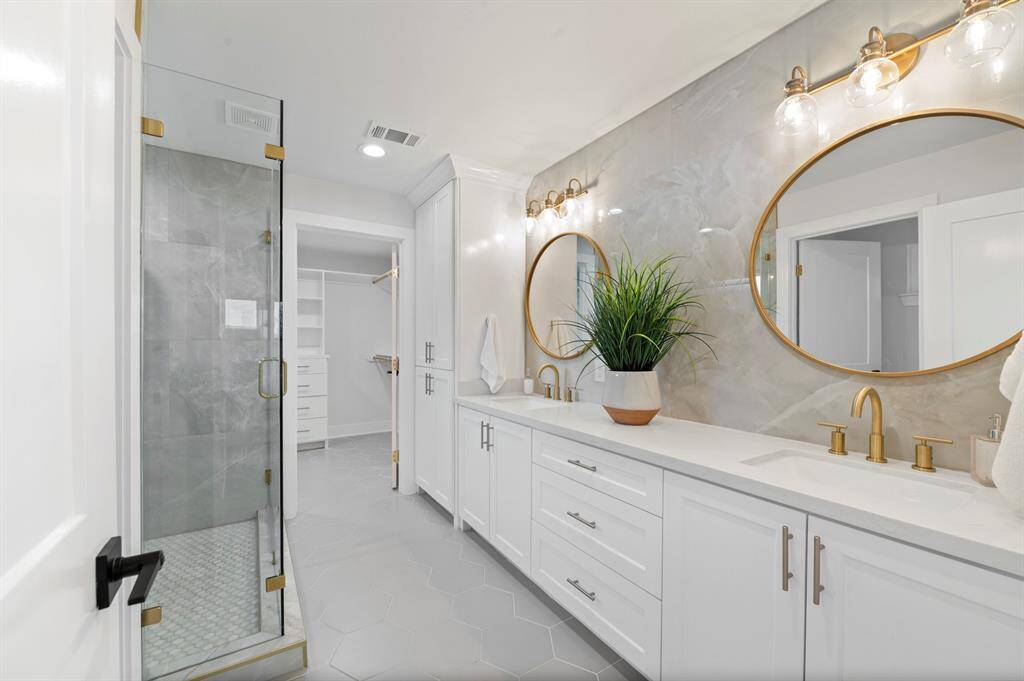 Enjoy a spa-worthy ensuite with a glass walk-in shower, dual vanities, and stunning tilework—plus direct access to your dream closet.