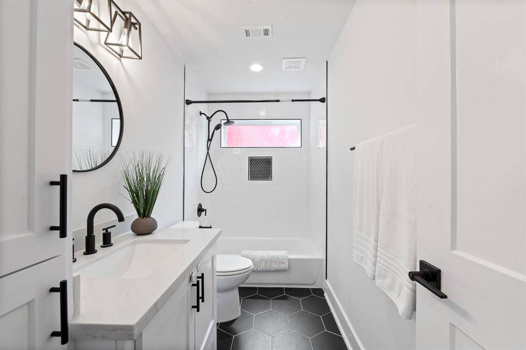 Crisp and contemporary with bold tile, matte black fixtures, and a deep soaking tub—this hall bath is anything but basic.