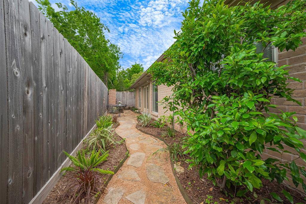 Fenced side yard has flagstone pathway and fresh landscaping