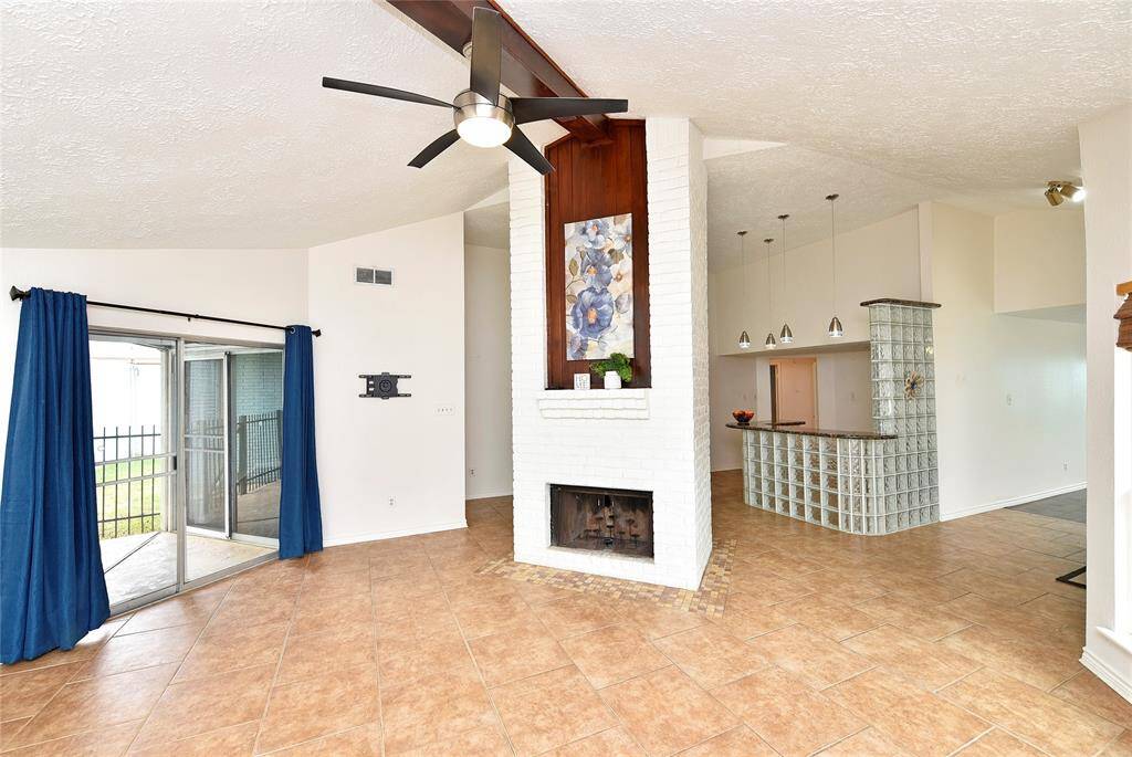 The family room features a central wood burning fireplace, topped with a brick mantel and wood inset. The soaring ceilings add a dramatic sense of space!