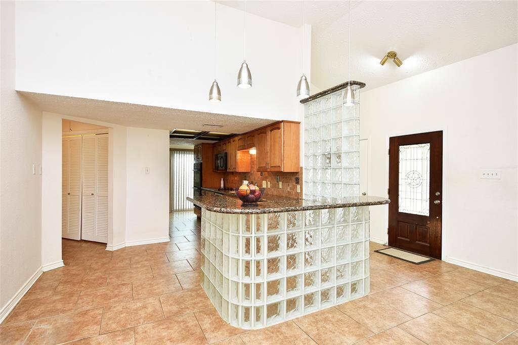 The hallway to the left goes to the secondary bedrooms, the utility room and the second full bath.  The glass block wall elegantly wraps around the serving area.