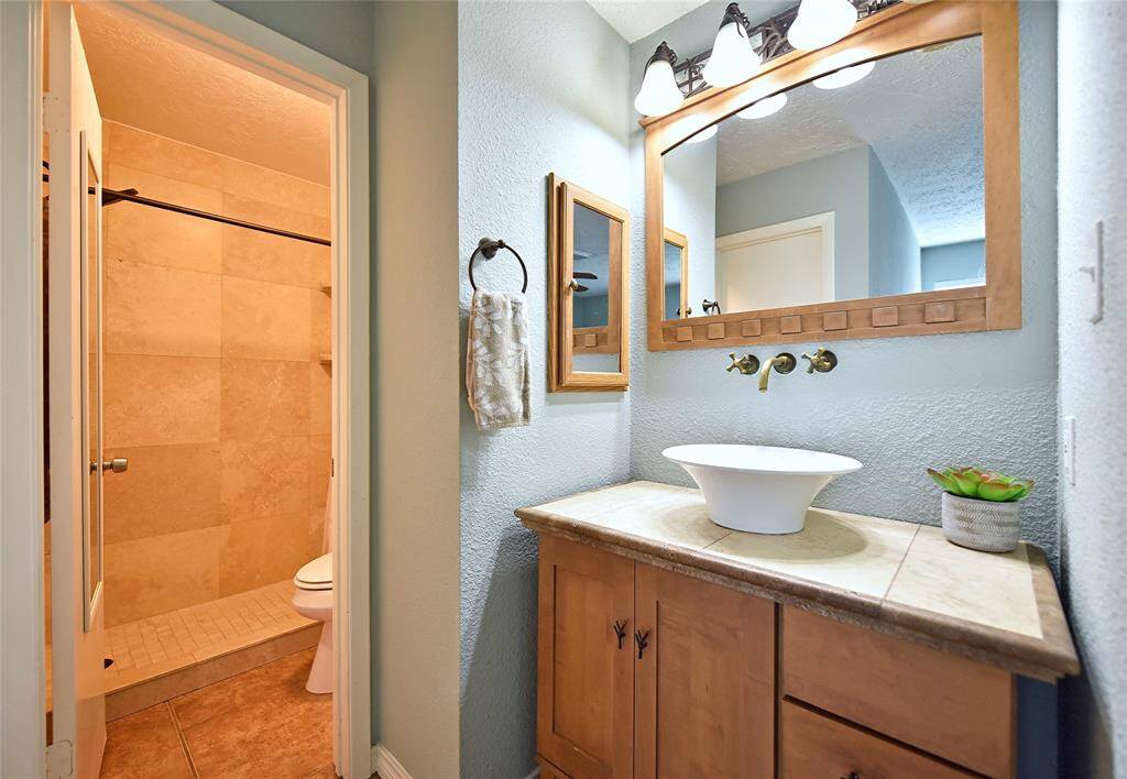 A pretty ceramic vessel sink, and wall mounted faucet are a great addition to the bathroom. Lots of storage in the furniture grade vanity! When the bathroom was remodeled, the old tub was removed to create a step-in shower.
