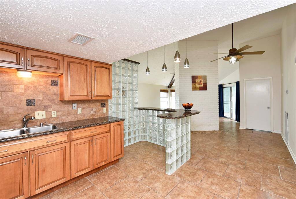 Very cool glass block and granite breakfast and serving bar, with pendant lights overhead.  You could also put a breakfast table in this space. The end of the base cabinet features cookbook or display shelving and wine bottle storage.