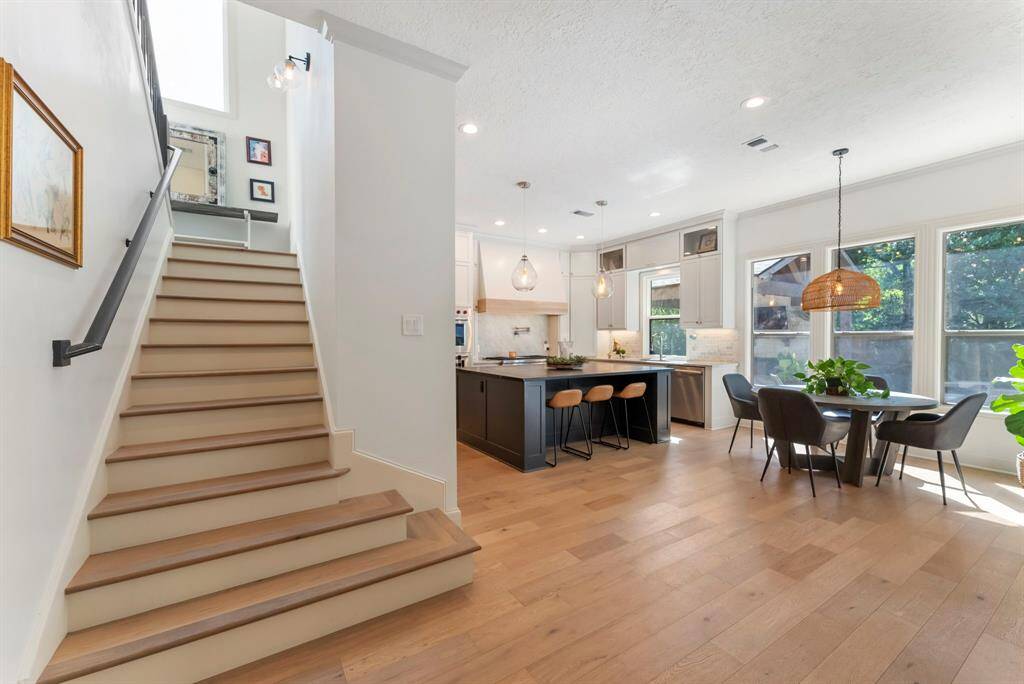 Open kitchen and breakfast area with a beautifully crafted wood staircase, providing access to attic space or offering the potential for a future upstairs build-out!