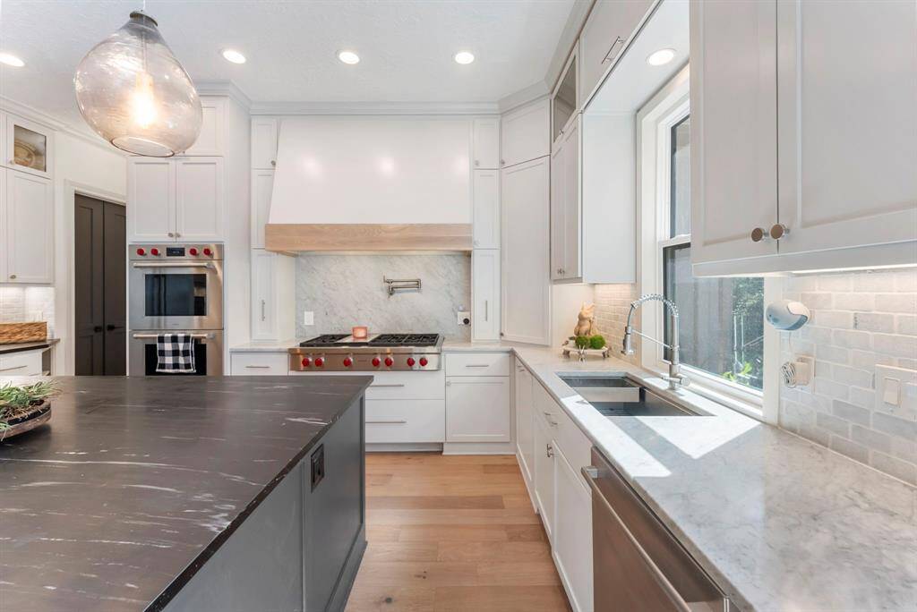 An incredible kitchen renovation showcases top-of-the-line Wolf appliances, luxurious Carrara and soapstone countertops, and a picture window over the sink!