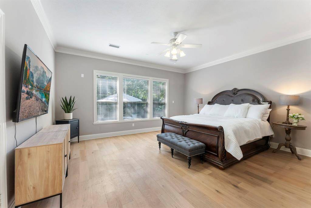 The spacious and light-filled primary suite features large windows and direct access to the back patio, creating a serene retreat with indoor-outdoor flow.