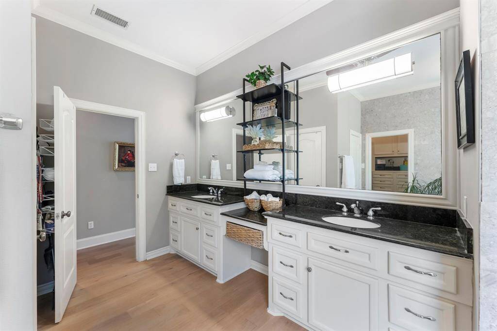 The spa-like primary bathroom showcases dual sinks, large mirror, and elegant European oak floors, combining luxury with everyday comfort.
