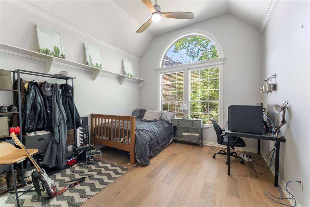 A spacious secondary bedroom features a vaulted ceiling, generous closet, and a window that brings in soft natural light.