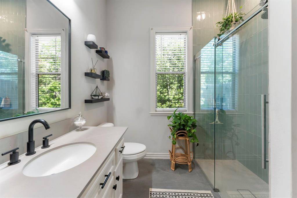 A recently updated full guest bathroom offers a sleek walk-in shower with floor-to-ceiling tile.