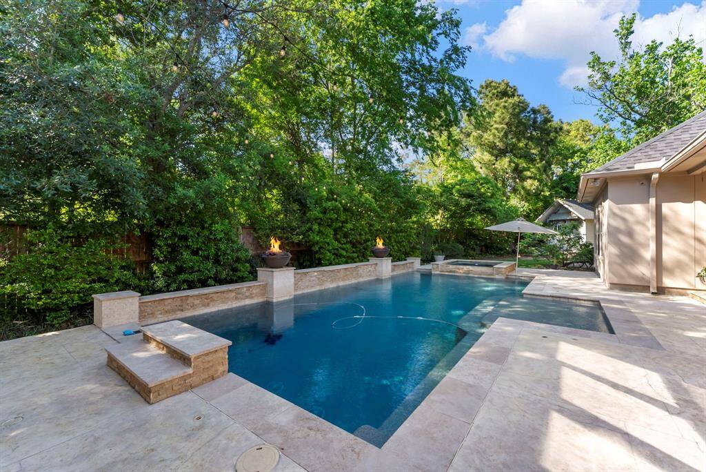 Ample decking surrounds the pool and spa, offering plenty of space for lounging and entertaining. The pool reaches a depth of approximately 8.5 feet at its deepest point.