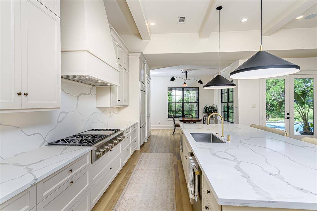Gorgeous quartz countertops with gold fixtures, custom cabinets and vent hood