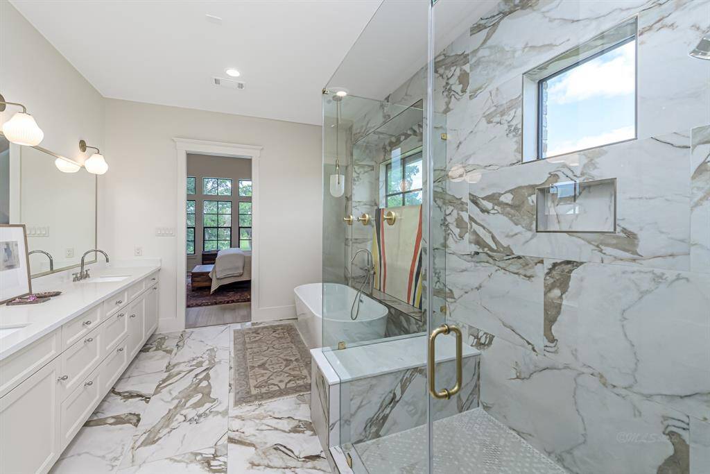 Primary bathroom with gold fixtures and marble tile