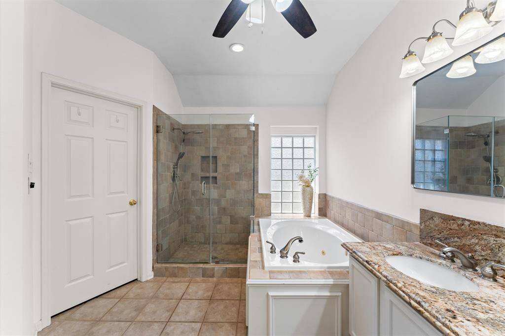 The garden tub invites you to unwind in a warm soak, while the separate shower adds everyday convenience. A ceiling fan keeps the space feeling fresh and comfortable.
