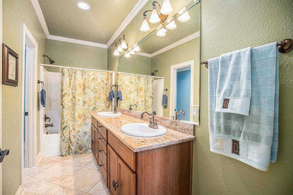 The primary ensuite bathroom is well-appointed, featuring a dual-sink vanity, a walk-in closet, and elegant crown molding.