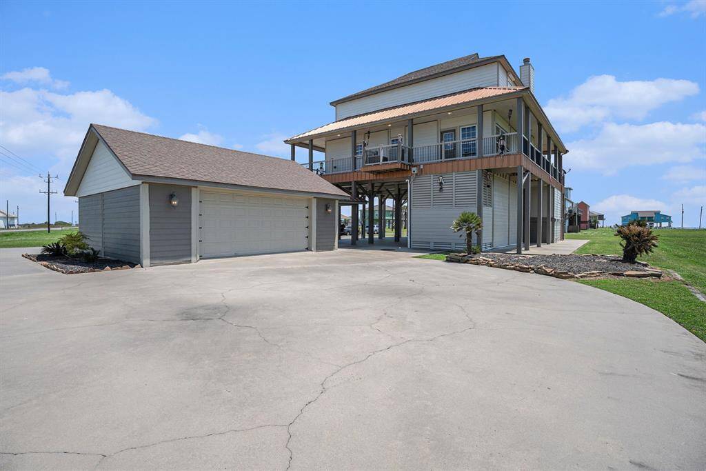 A generous driveway and detached garage are prominent features of the daytime exterior, complemented by a landscaped yard. The elevated design offers covered parking and bright, natural light.
