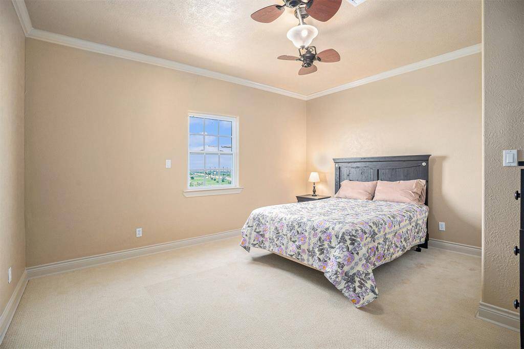 This oversized secondary bedroom, situated conveniently at the top of the stairs, offers a remarkable sense of spaciousness. The generous dimensions provide ample room for a variety of furniture arrangements, creating a comfortable and versatile living area. Adding a touch of elegance, refined crown molding gracefully accents the perimeter of the room, enhancing its overall aesthetic appeal.