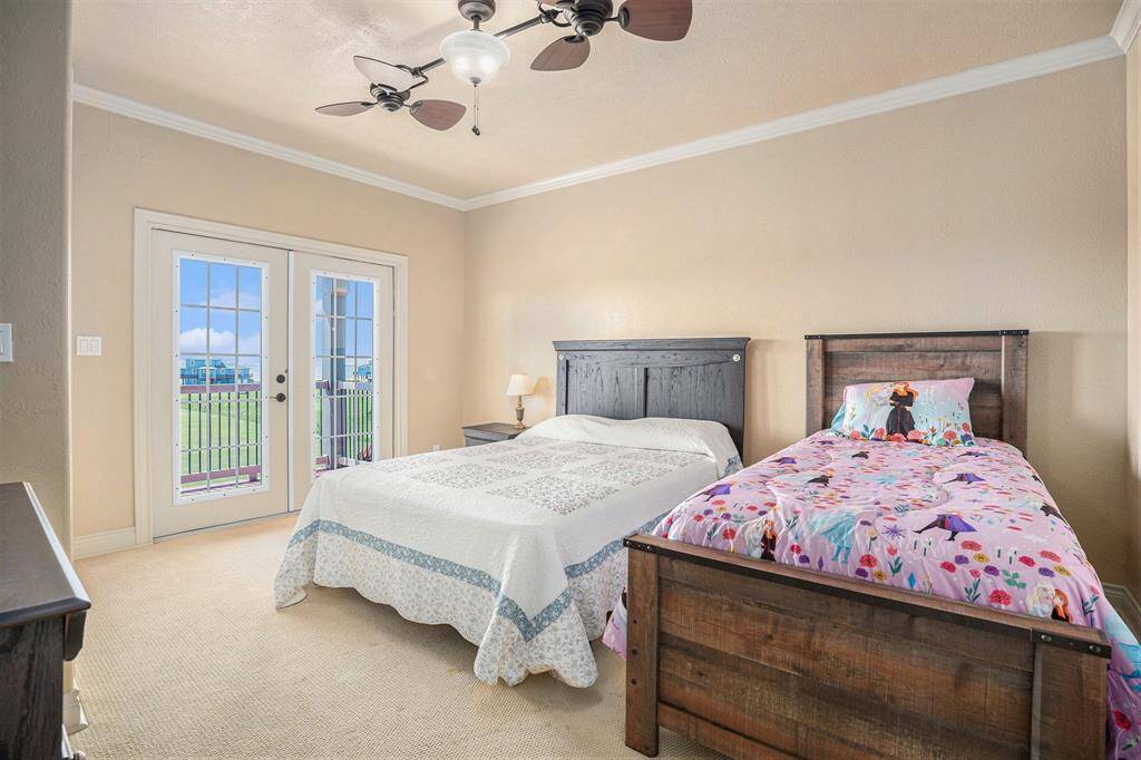 Discover another spacious secondary bedroom, large enough to comfortably fit two beds, offering exceptional versatility. French doors provide a lovely connection to the outside deck, perfect for relaxation. Crown molding adds a touch of sophisticated style to the room.