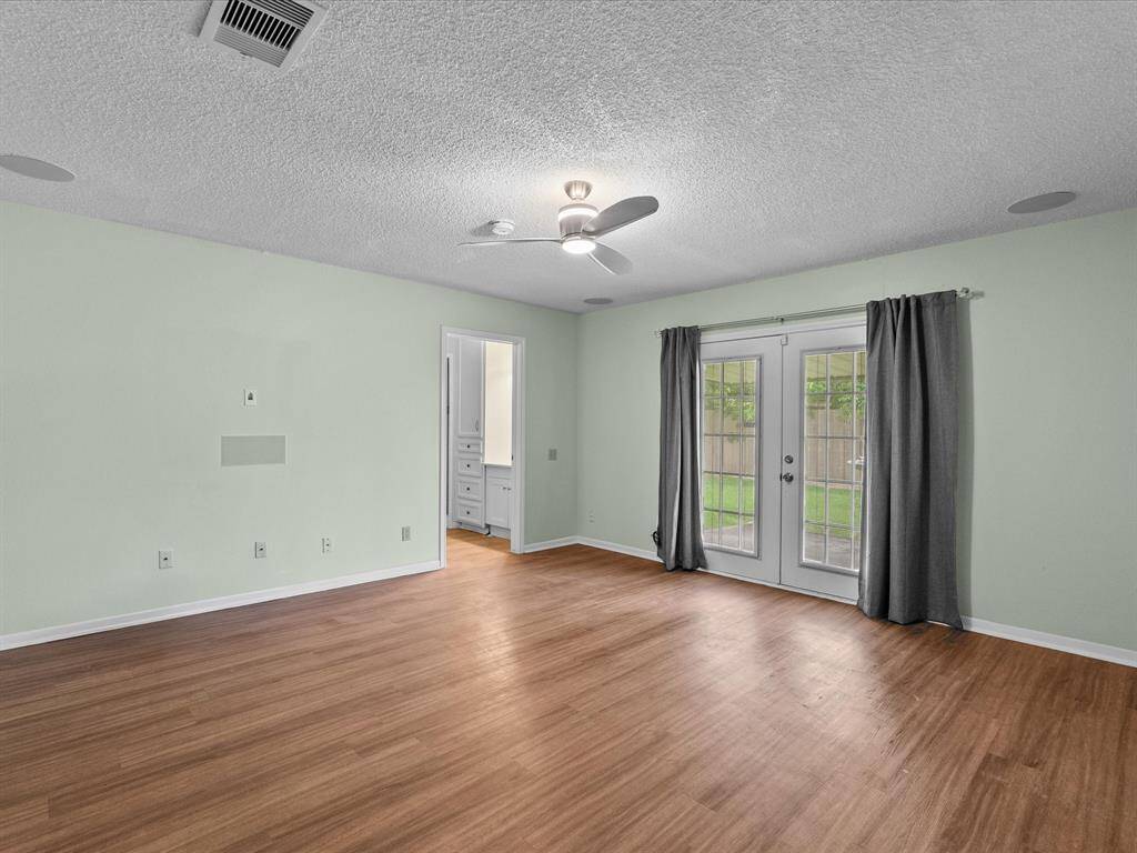 Primary bedroom w/Wood like tile,french doors opening to back yard. Perfect for enjoying early morning coffee or tea.