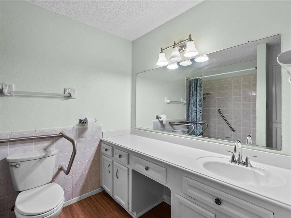 This room features a soft green wall color, a ceiling fan with a light, wood-like flooring, and a large window that provides ample natural light.
