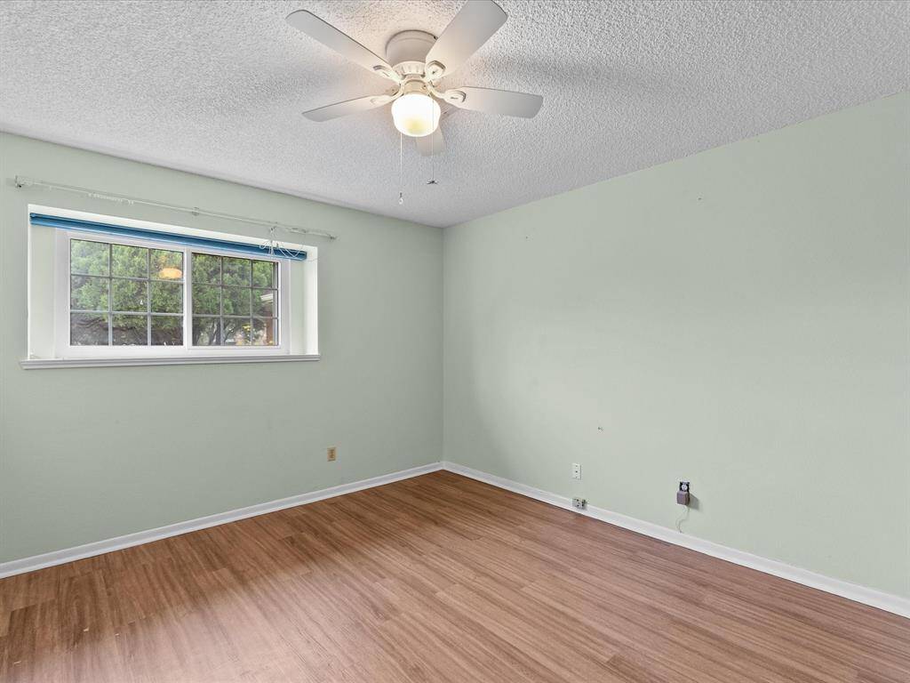 Bedroom #3 with wood like floors, ceiling fan, and large windows with lots of natural light.
