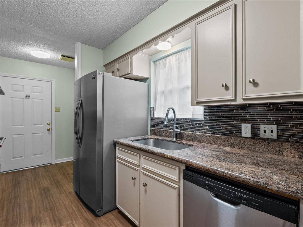 Granite countertops with sleek backsplash and wood type tile flooring compliments a kitchen that is functional and an abundance of storage space.