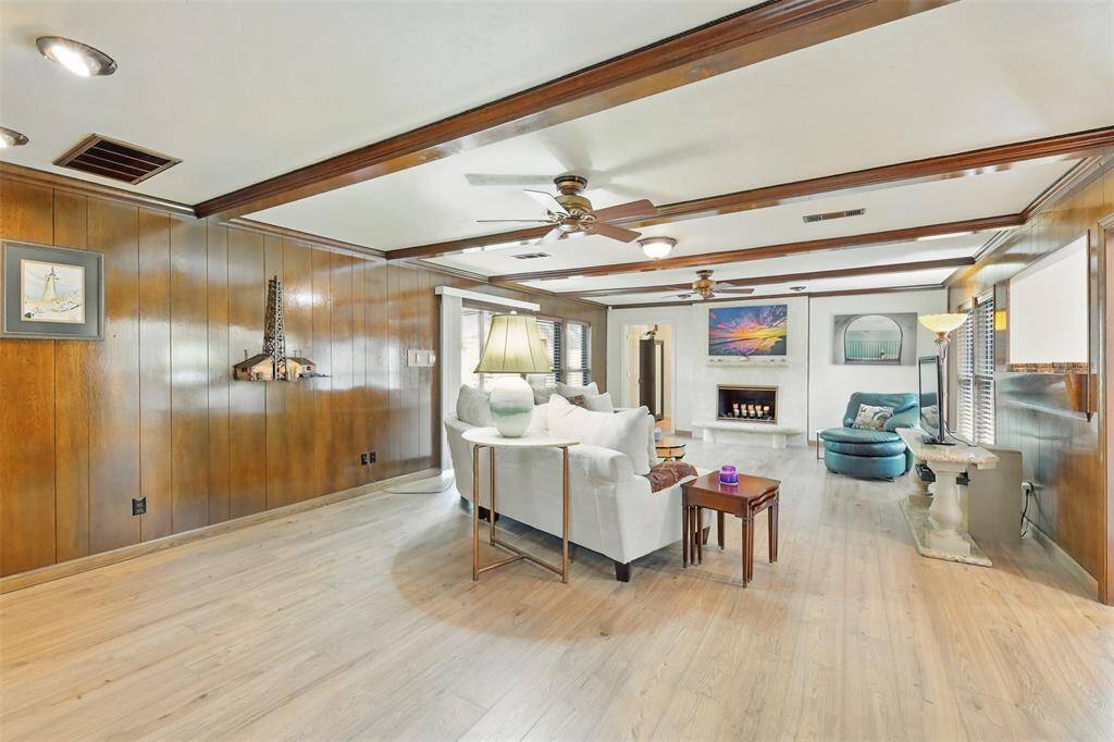 The spacious den has paneled walls, luxury vinyl plank floors,  two ceiling fans and a one of kind Cordova Shell Stone fireplace designed and crafted by the seller.