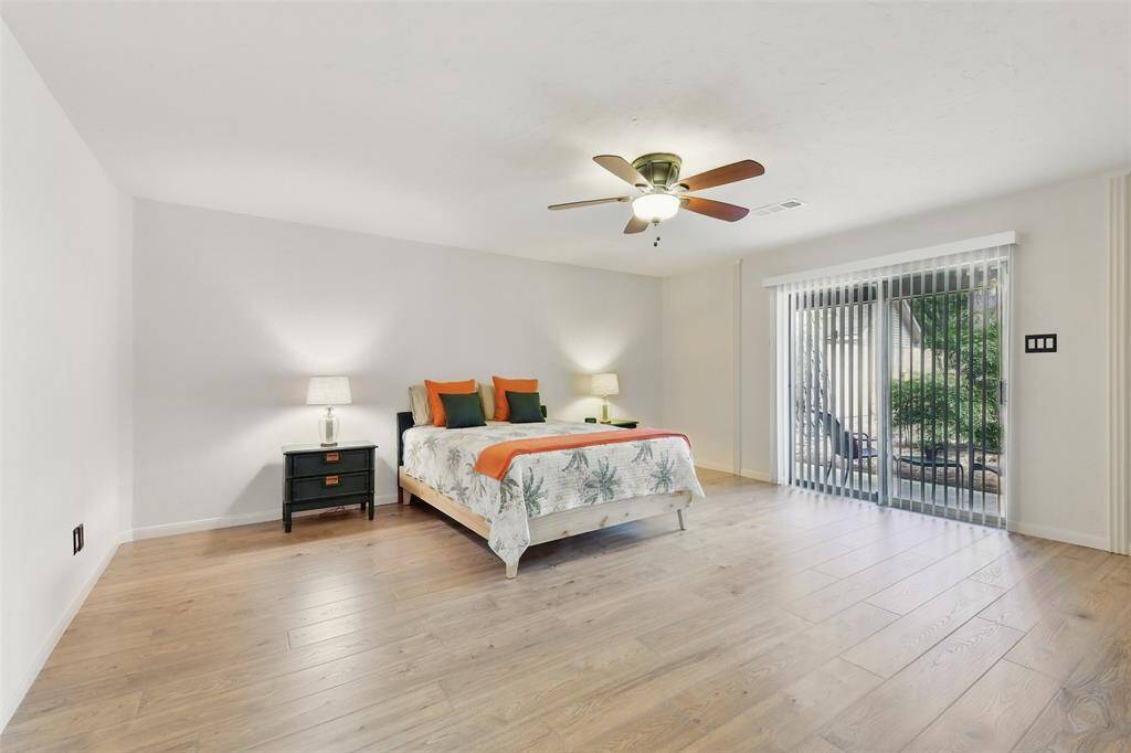 The spacious primary bedroom has a ceiling fan, luxury vinyl plank floors (2023) and access to one of the back patios through the sliding glass door.