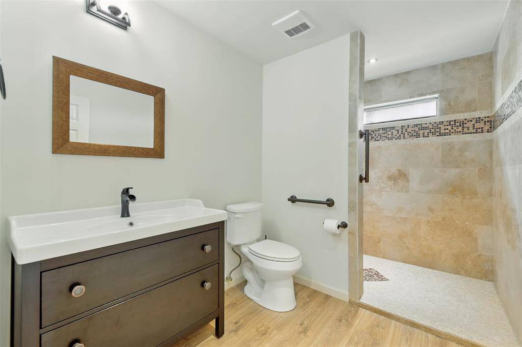The mother in-law suite bathroom has an updated vanity and a oversized standing shower with tile surround.