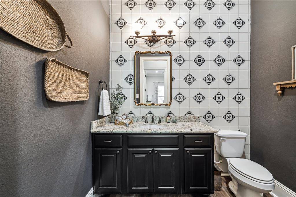 Conveniently located on the first floor for guests, the powder bathroom features a granite vanity, custom tile, designer paint and a stylish framed mirror with coordinating vanity lights above.