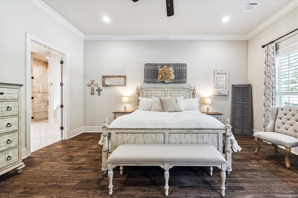 Tucked away for ultimate privacy, this elegant primary suite is a peaceful haven styled with soft neutral tones, rich wood-look tile flooring, and plenty of space for oversized furnishings. A glass door offers direct access to the pool and patio, seamlessly blending indoor comfort with outdoor tranquility. The spa-like ensuite showcases separate vanities, a jetted soaking tub, an oversized walk-in shower, and it opens to a private bonus room with limitless possibilities.