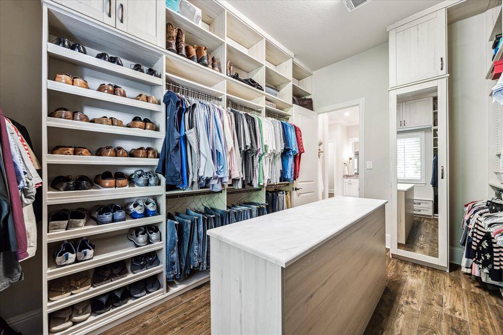 Shop until you drop! This massive custom walk-in closet can take it. Thoughtfully designed with ample hanging space, built-in cubbies, shoe racks, and a convenient center island, it offers both style and storage in equal measure.