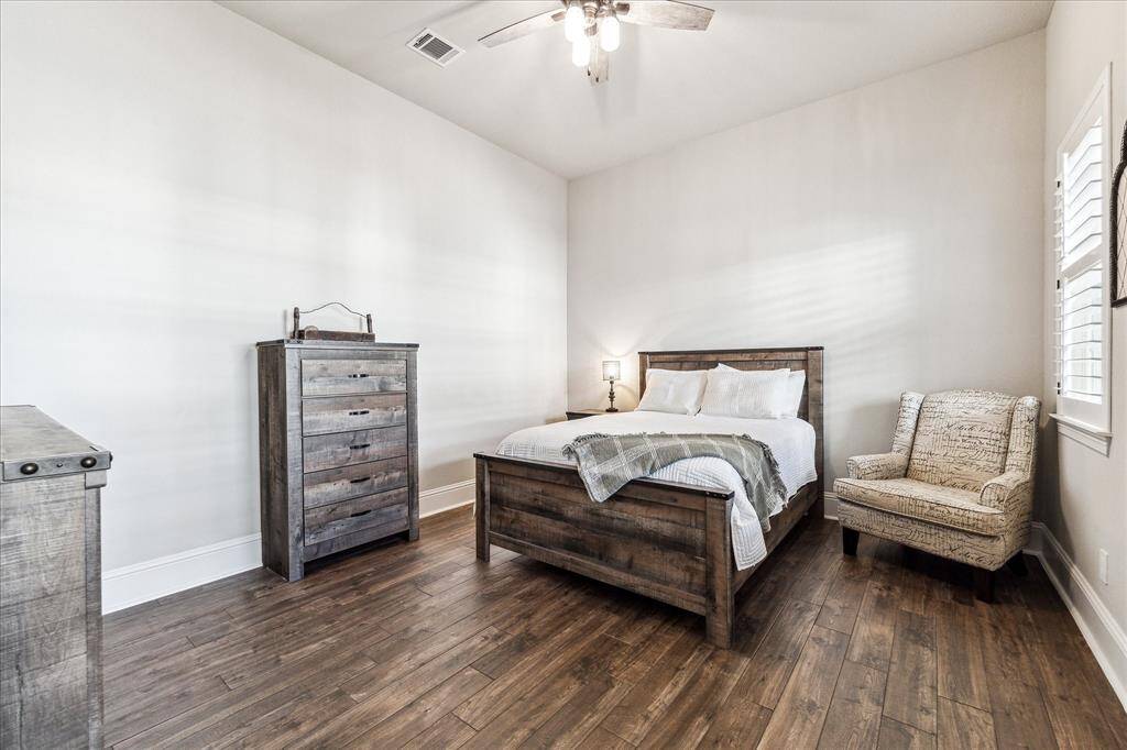 The first-floor guest suite features beautiful wood-look tile flooring, soft neutral finishes, a spacious closet, and ensuite access to a full bathroom. Ideal for multigenerational living or long-term guests, this flexible space offers comfort, privacy, and convenience all on the main level.