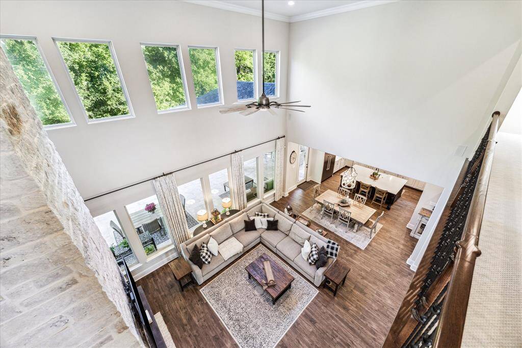 The family room is just as captivating from the second-floor landing, where a soaring 24' ceiling and a dramatic wall of stacked windows frame breathtaking views of the patio, pool, spa, and the lush wooded area behind the home.