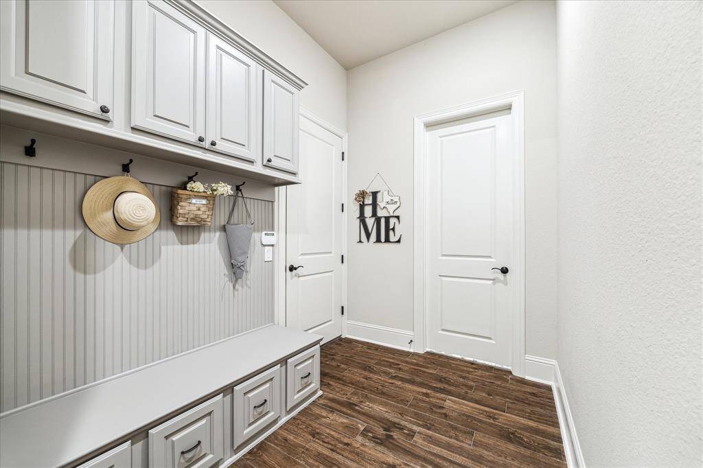 This stylish mud area is designed to keep daily life running smoothly, featuring custom cabinetry, a built-in bench, and hooks for coats, hats, and bags offering the perfect blend of function and charm.