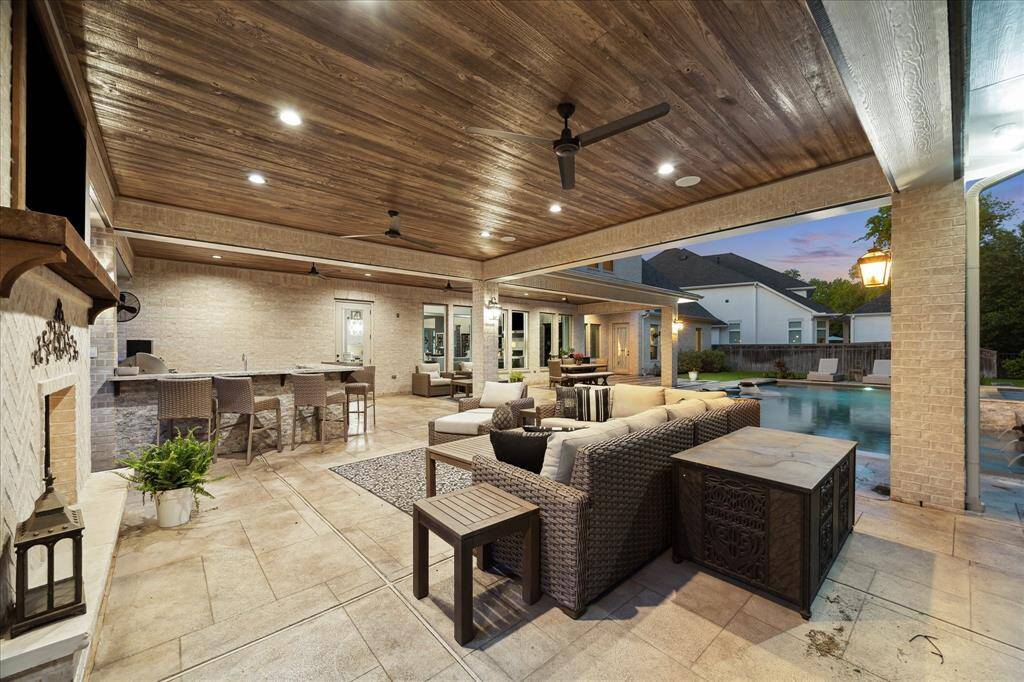 This expansive covered patio is an entertainer’s dream, featuring a fully equipped summer kitchen with bar seating, stainless steel components and generous prep space. Overhead, a wood-paneled ceiling with recessed lighting and ceiling fans adds warmth and comfort, while the outdoor fireplace and surround sound system set the perfect tone for cozy evening gatherings by the pool.