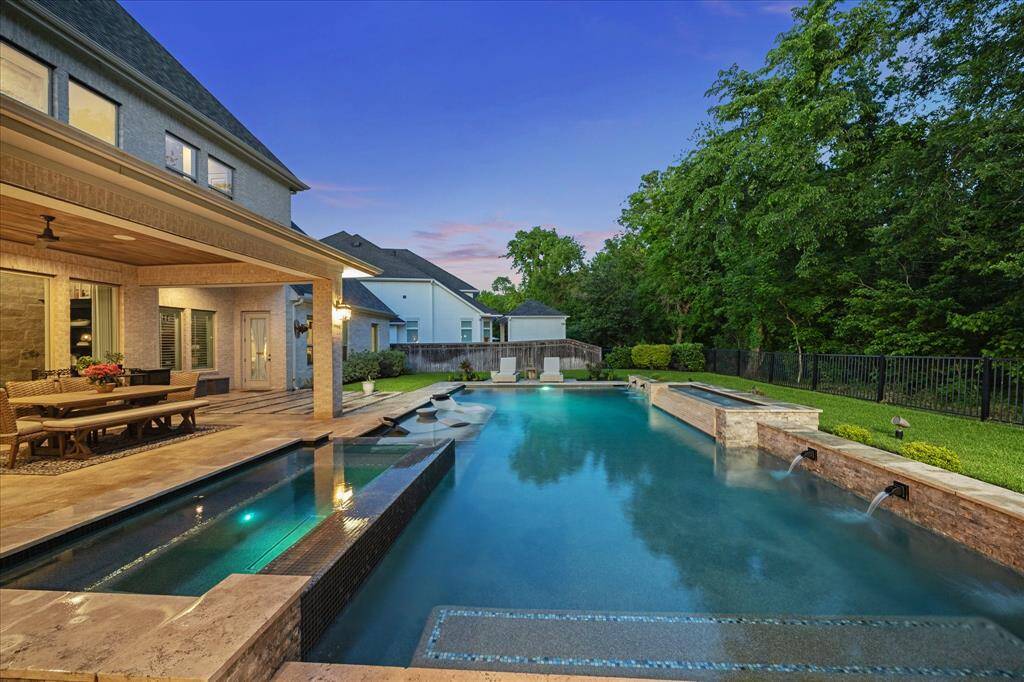This spectacular backyard oasis is a true showstopper, featuring a relaxing spa and a heated and chilled pool with elegant water features, ambient lighting, and expansive tanning ledges perfect for lounging in style. Surrounded by nature with a lush wooded backdrop and no back neighbors, the setting is as private as it is picturesque ideal for quiet mornings, lively evening gatherings, and everything in between.