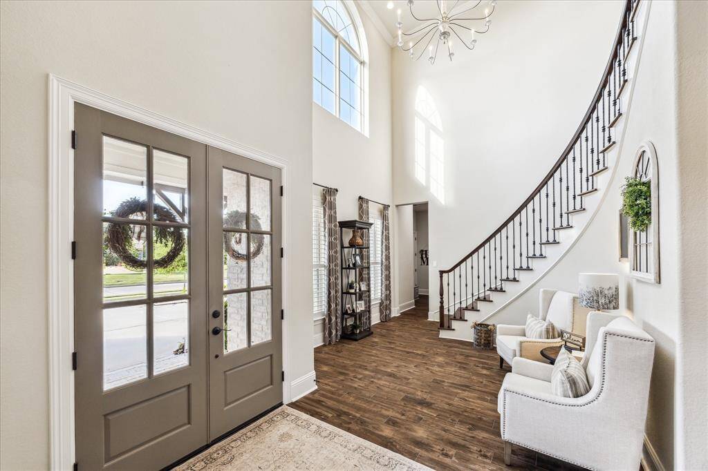 This impressive foyer welcomes you with warmth and elegance, featuring a soaring ceiling with a stylish chandelier, rich wood-look tile flooring, and a grand sweeping staircase. It’s a beautiful first impression with a hint of the timeless style and thoughtful design you will find throughout the home.