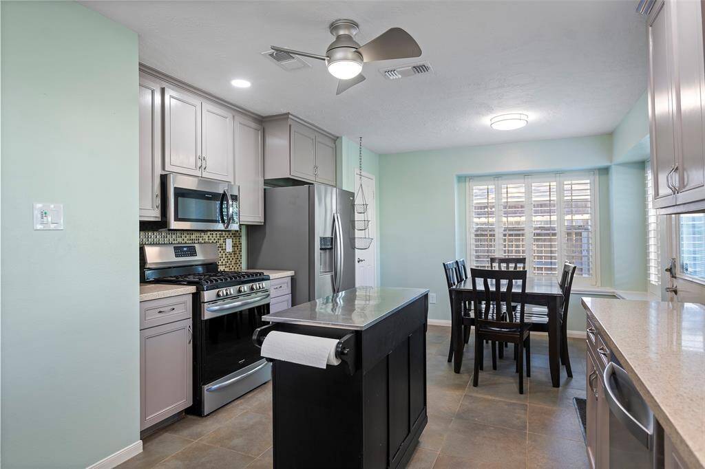 Thoughtfully laid out kitchen with modern stainless-steel appliances, elegant cabinetry, and a central island. Enjoy natural light through large windows in the cozy dining area, perfect for family meals.