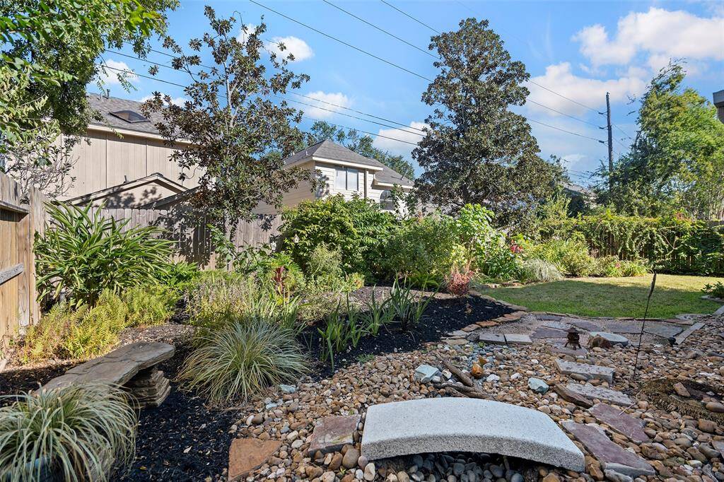 Discover a tranquil backyard oasis featuring lush landscaping, mature trees, and a charming stone pathway. Perfect for relaxation and outdoor gatherings.