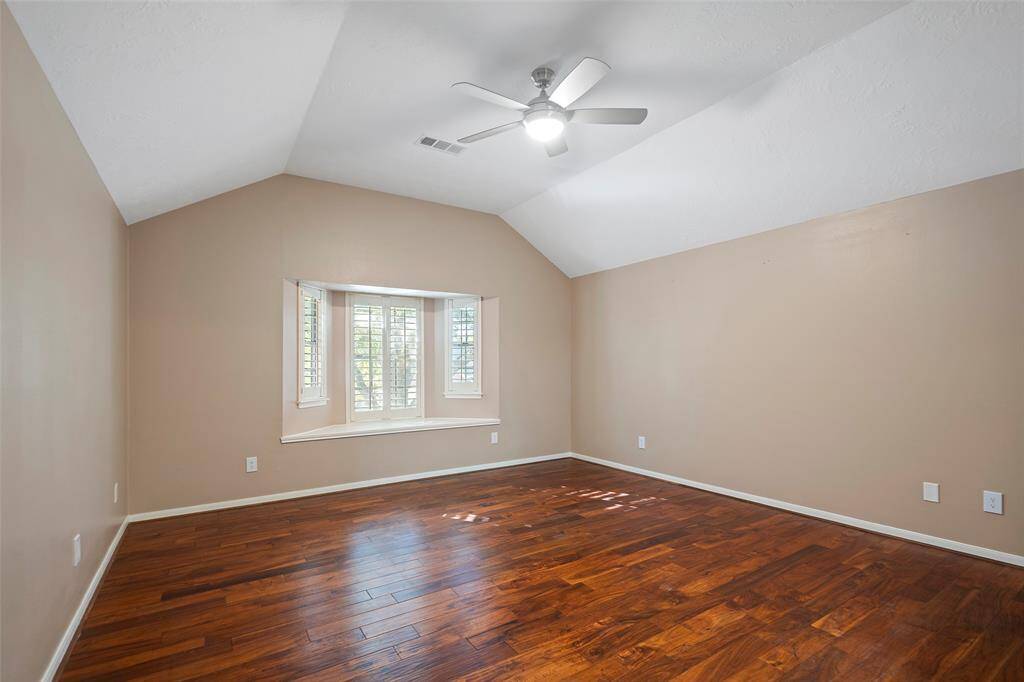 Discover this inviting room featuring elegant hardwood floors, a vaulted ceiling, and a charming bay window that floods the space with natural light.