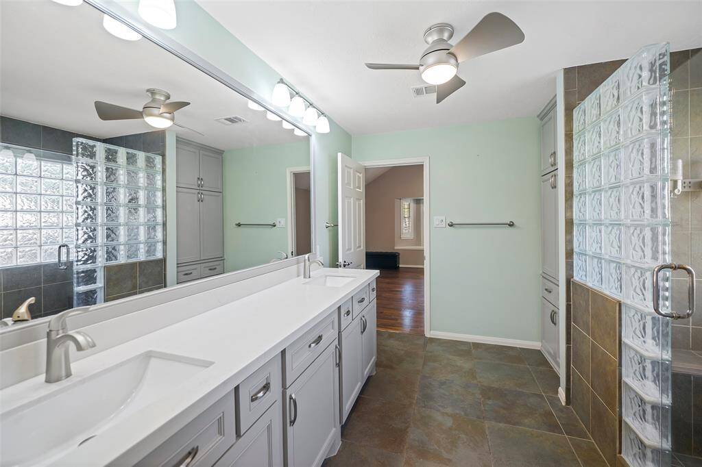 This spacious bathroom features a sleek double vanity, modern fixtures, and a luxurious glass-enclosed shower, offering a perfect blend of style and functionality.