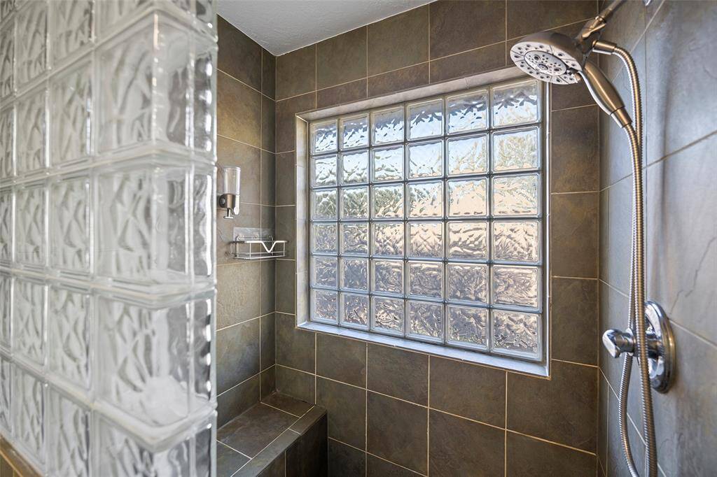 Experience luxury in this elegant shower featuring sleek tile finishes and a stylish glass block window, offering both privacy and natural light.