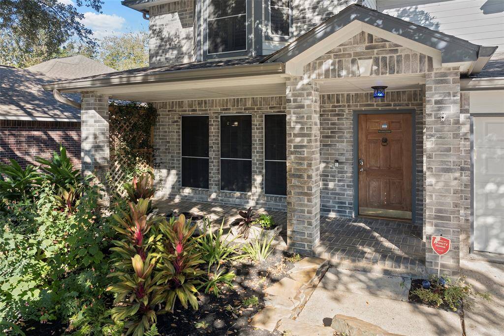 This inviting property features a welcoming front porch and elegant brickwork.