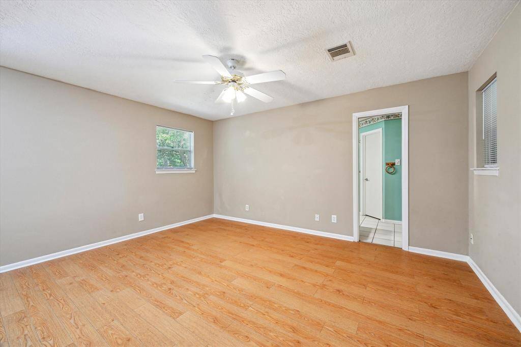Primary bedroom with ample space and natural light, viewed from the hallway.