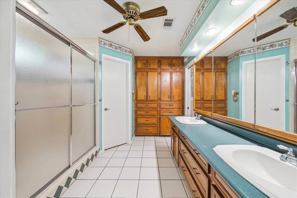 Spacious primary bathroom featuring built-ins and dual walk-in closets for ample storage.