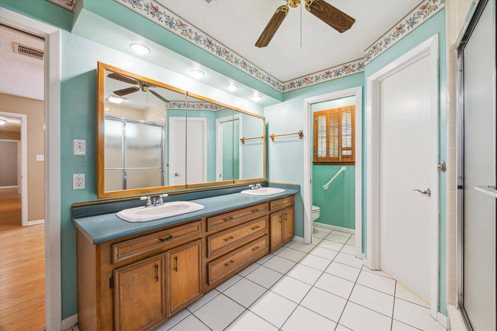 Spacious primary bathroom featuring dual sinks, ample storage, and a stylish, vintage design.
