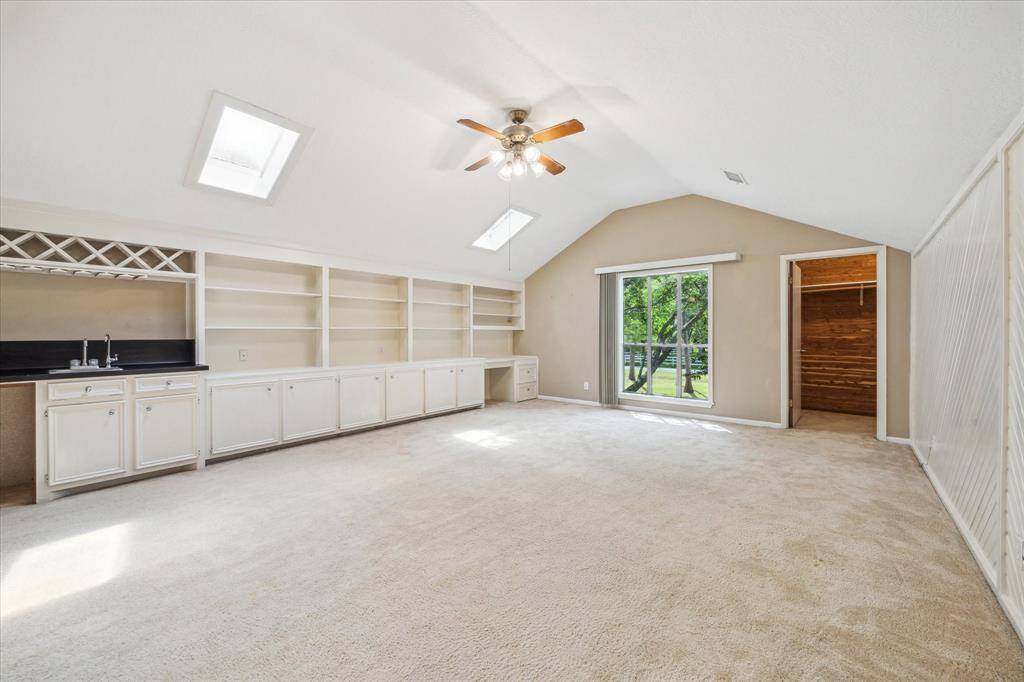 Discover the spacious upstairs living area, featuring abundant natural light, built-in shelving, and a convenient wet bar. Ideal for relaxation or entertaining.