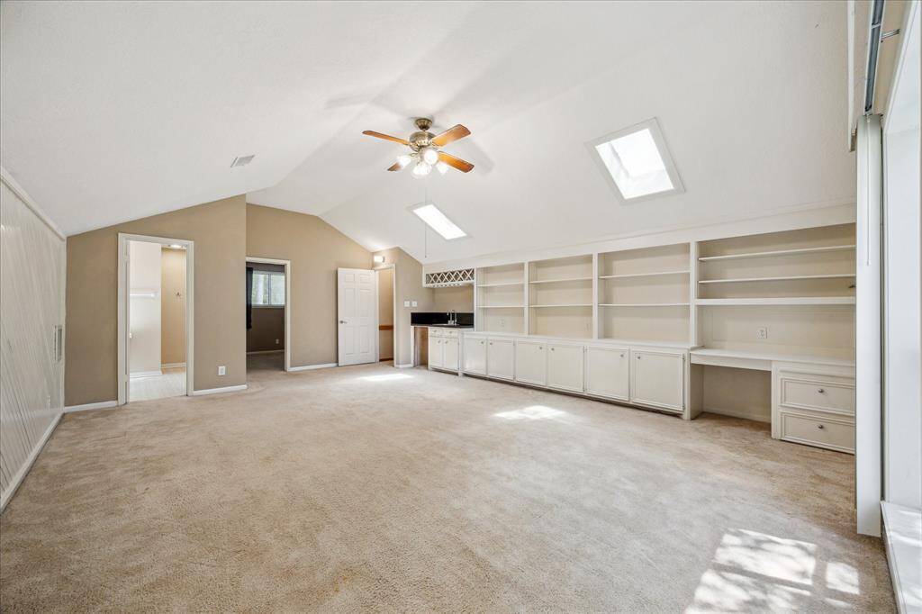 Spacious upstairs den with built-in shelving, a bar sink, and space for a refrigerator or ice maker.