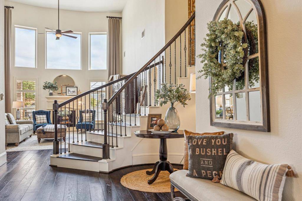 At center stage, the grand sweeping staircase showcases rich wood railings and intricate iron balusters. Overhead, a towering rotunda ceiling crowned with an elegant chandelier completes the scene, creating a dramatic and unforgettable first impression.
